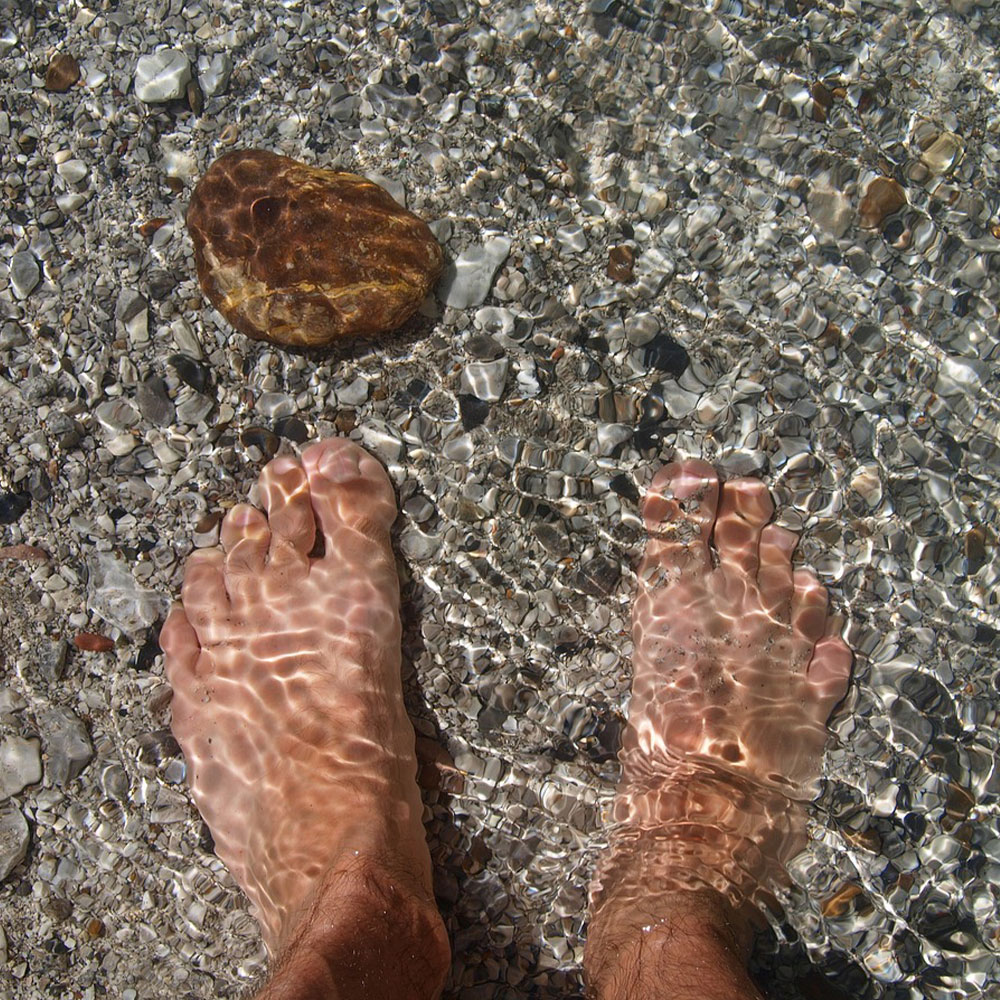 Női láb a vízben a tengerparton